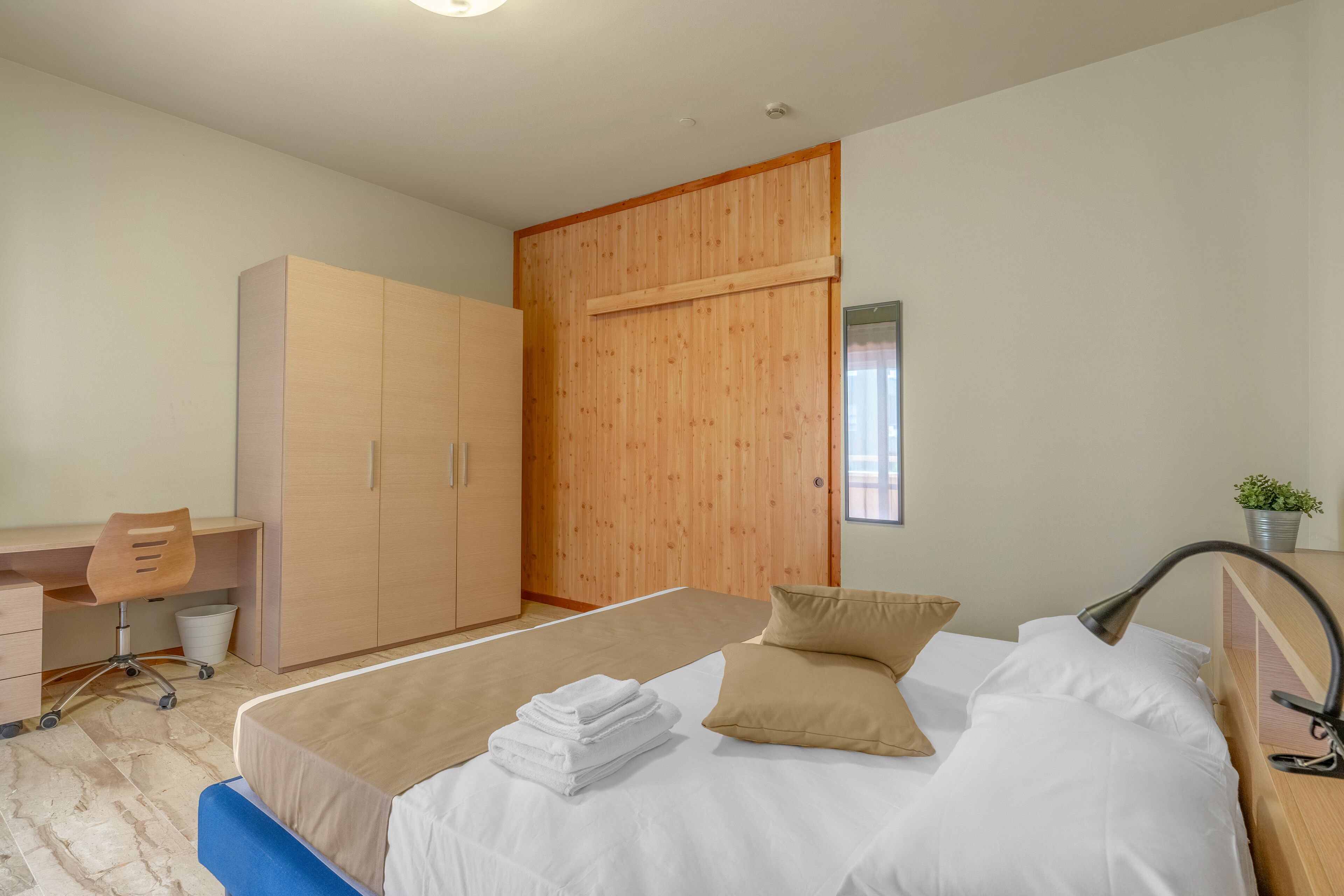 Een slaapkamer met een bed, een bureau en een kledingkast.