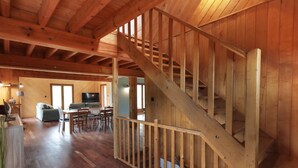 A spacious wooden interior with a staircase, a dining area, and a living room.