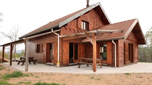 A rustic wooden cabin with a covered porch, a picnic table, and a small outdoor seating area.