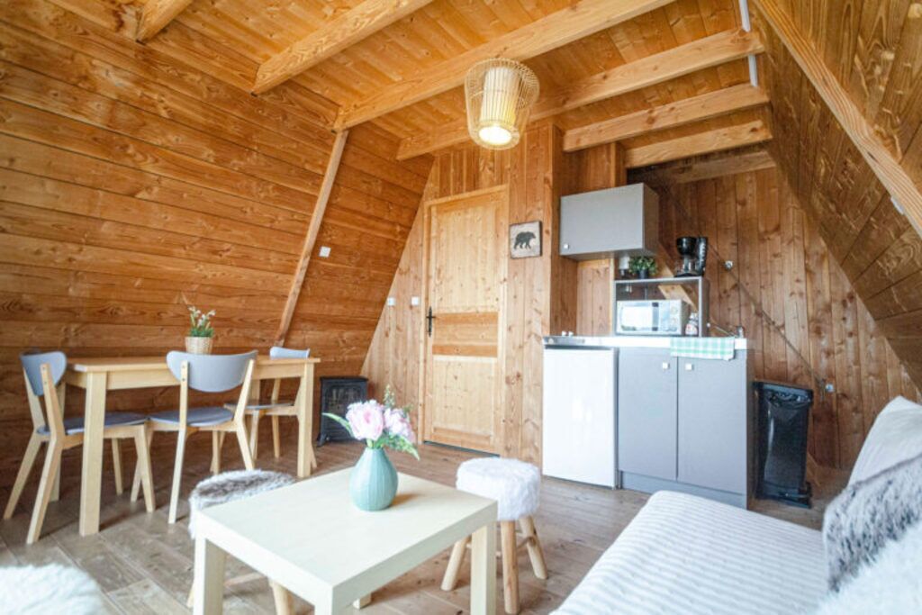 Ein gemütliches Holzhaus mit Essbereich, einer Küchenzeile und einem Bett.