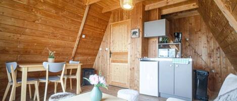 Ein gemütliches Holzhaus mit Essbereich, einer Küchenzeile und einem Bett.