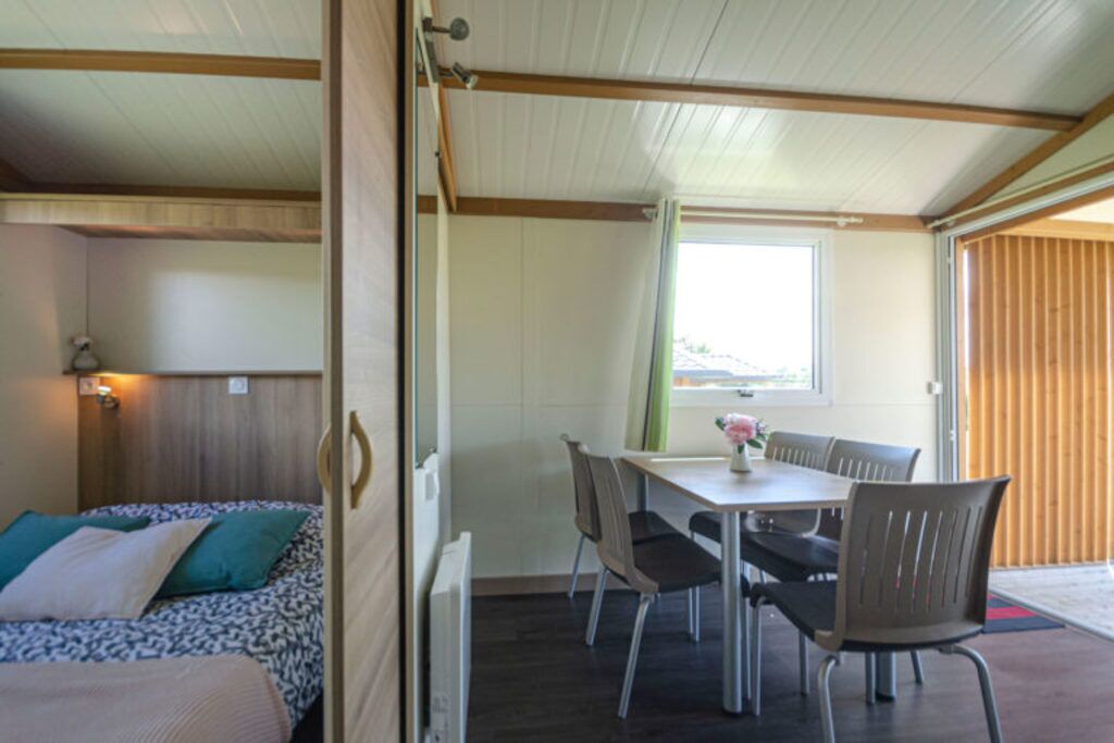 A compact room with a bed, a table with chairs, and a window.