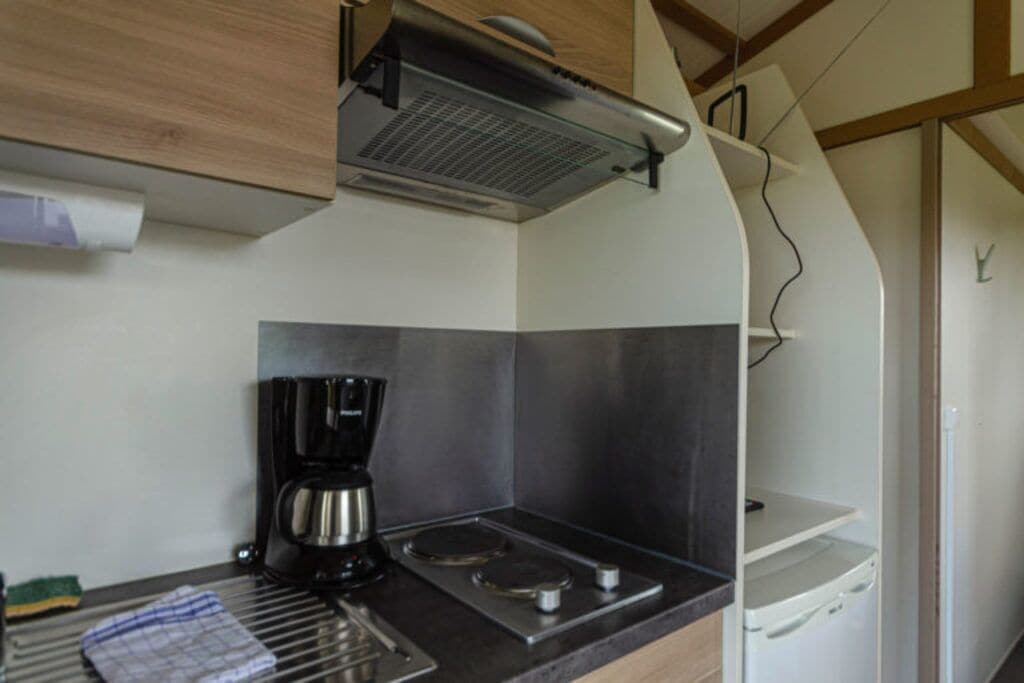 Een kleine keuken met een koffiezetapparaat, een fornuis en een magnetron.