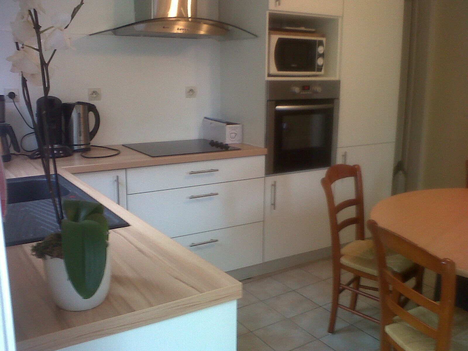 A compact kitchen with a microwave, oven, and a small dining table with chairs.