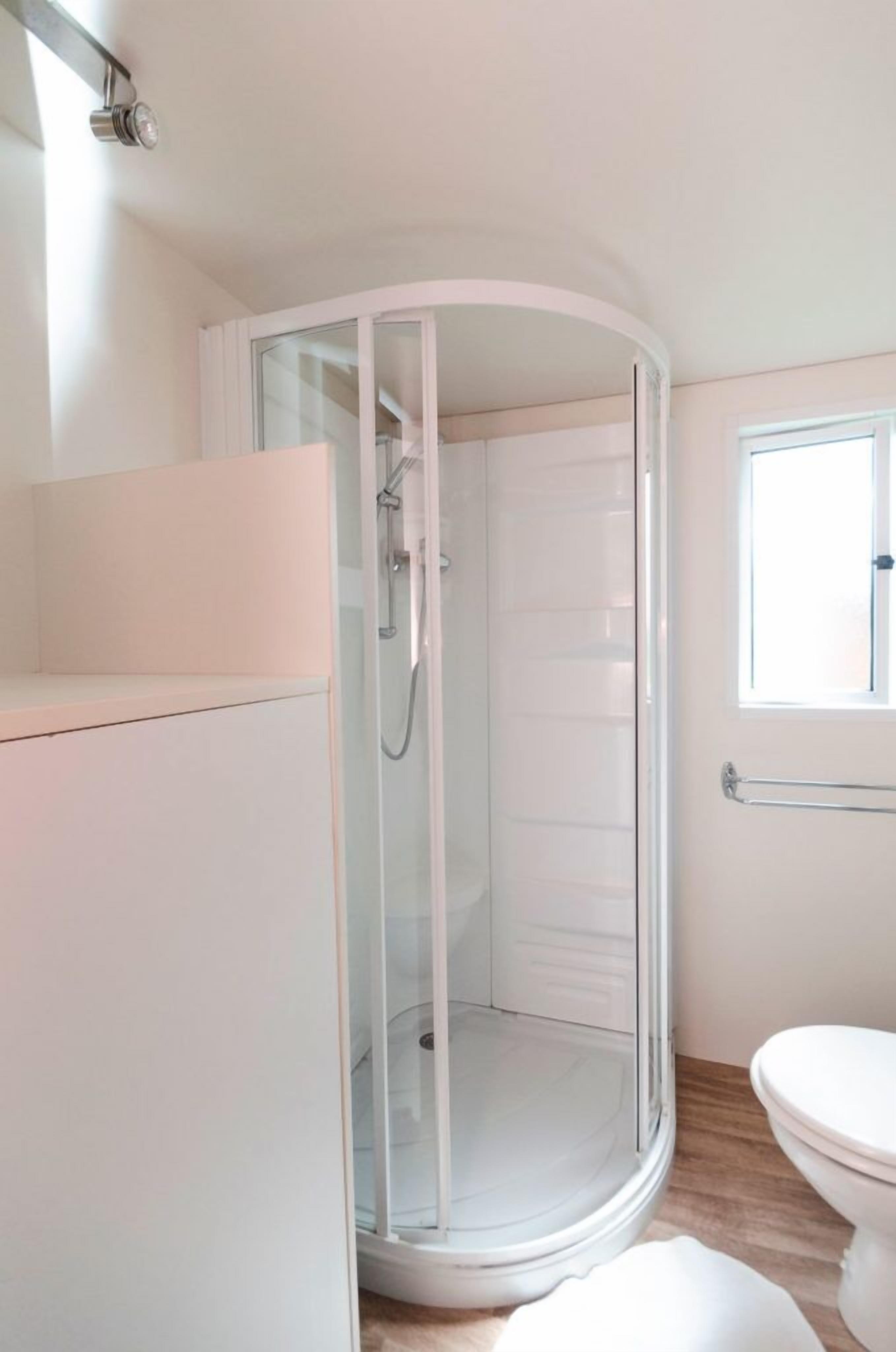 A modern bathroom with a glass-enclosed shower, a toilet, and a sink area.