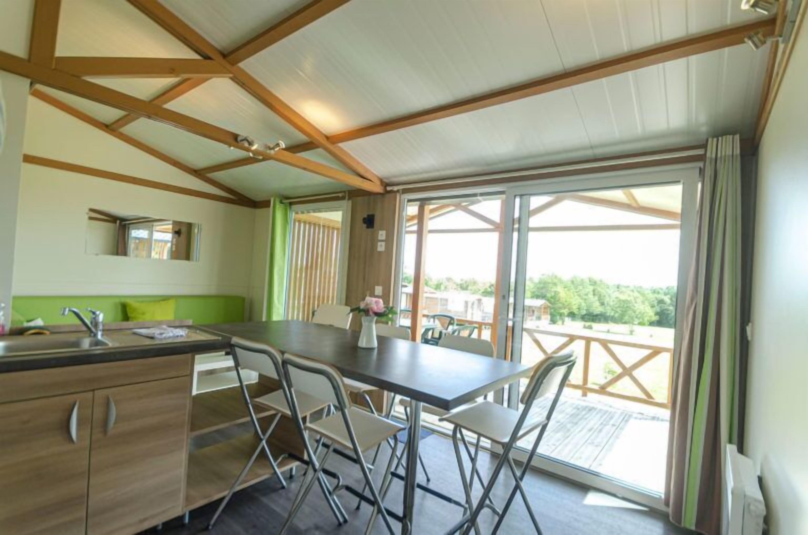 Une cuisine avec une table à manger, des chaises et une vue sur l’extérieur.