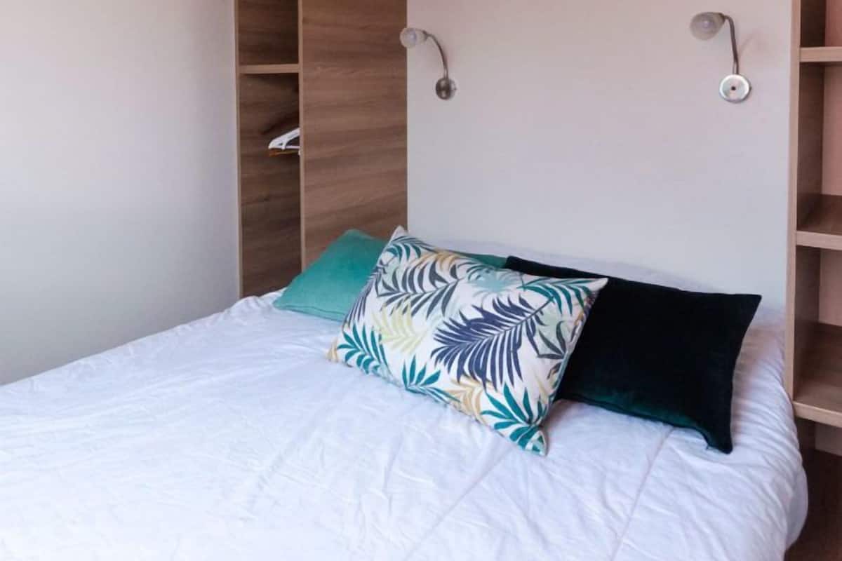 Een slaapkamer met een bed, een houten hoofdbord en ingebouwde planken.