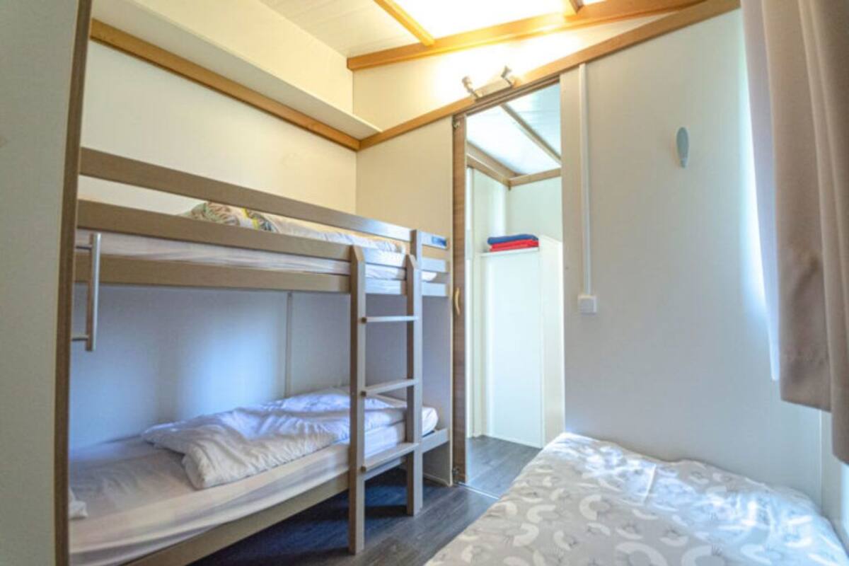 Een slaapkamer met een stapelbed, een bureau en een raam.