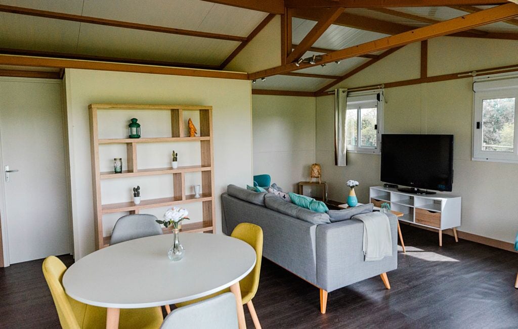 A modern living room with a sofa, a television, a dining table, and a bookshelf.