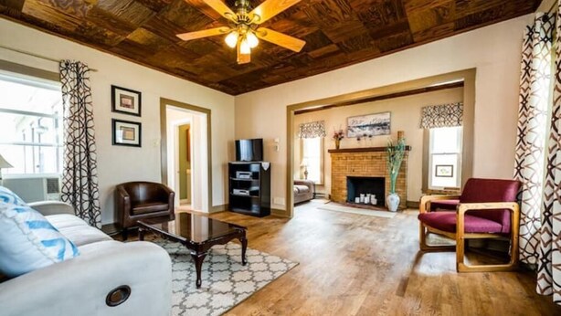 Un salon doté d’un plancher en bois, d’un ventilateur de plafond, d’une cheminée et d’un téléviseur.