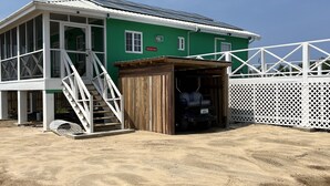 A green building with a covered garage and a white fence. - Cozy, comfortable, secure home with pool, outside San Pedro near Secret Beach (San Pedro)