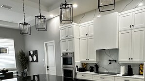 A modern kitchen with a large island, white cabinets, and pendant lighting. - Amazing Mansion on Toho (Kissimmee)