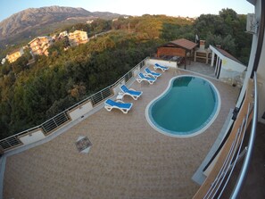 A rooftop pool area with lounge chairs, a swimming pool, and a view of a mountainous landscape. - Belvedere Apartments with Seaview (Bar)