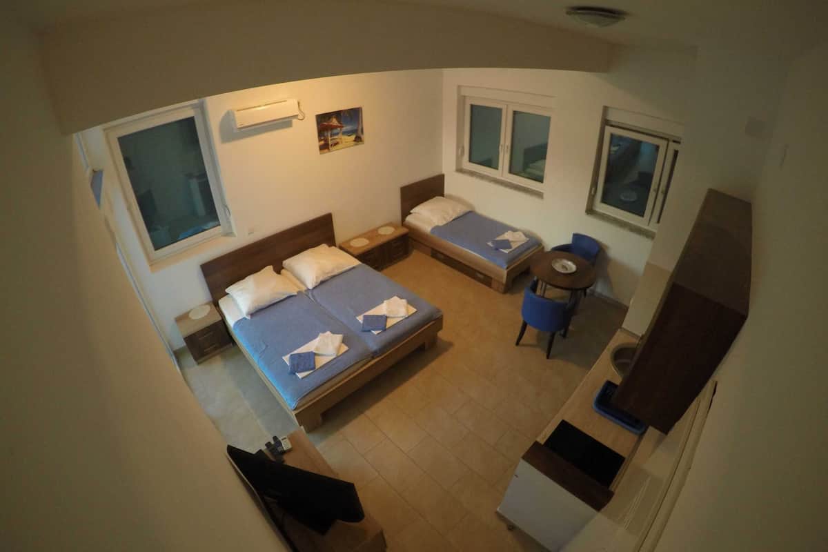 A compact hotel room with a bed, a small desk, a chair, and a window.