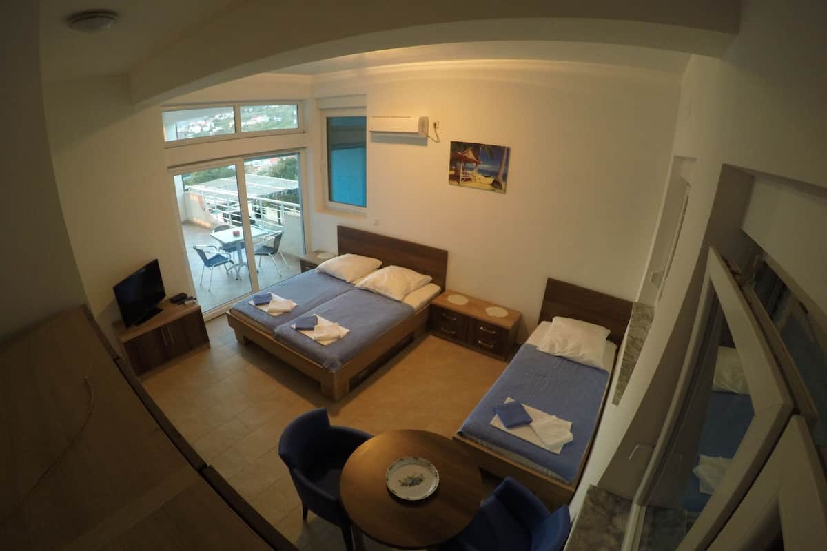 A hotel room with a bed, a desk, a chair, a table, and a TV.