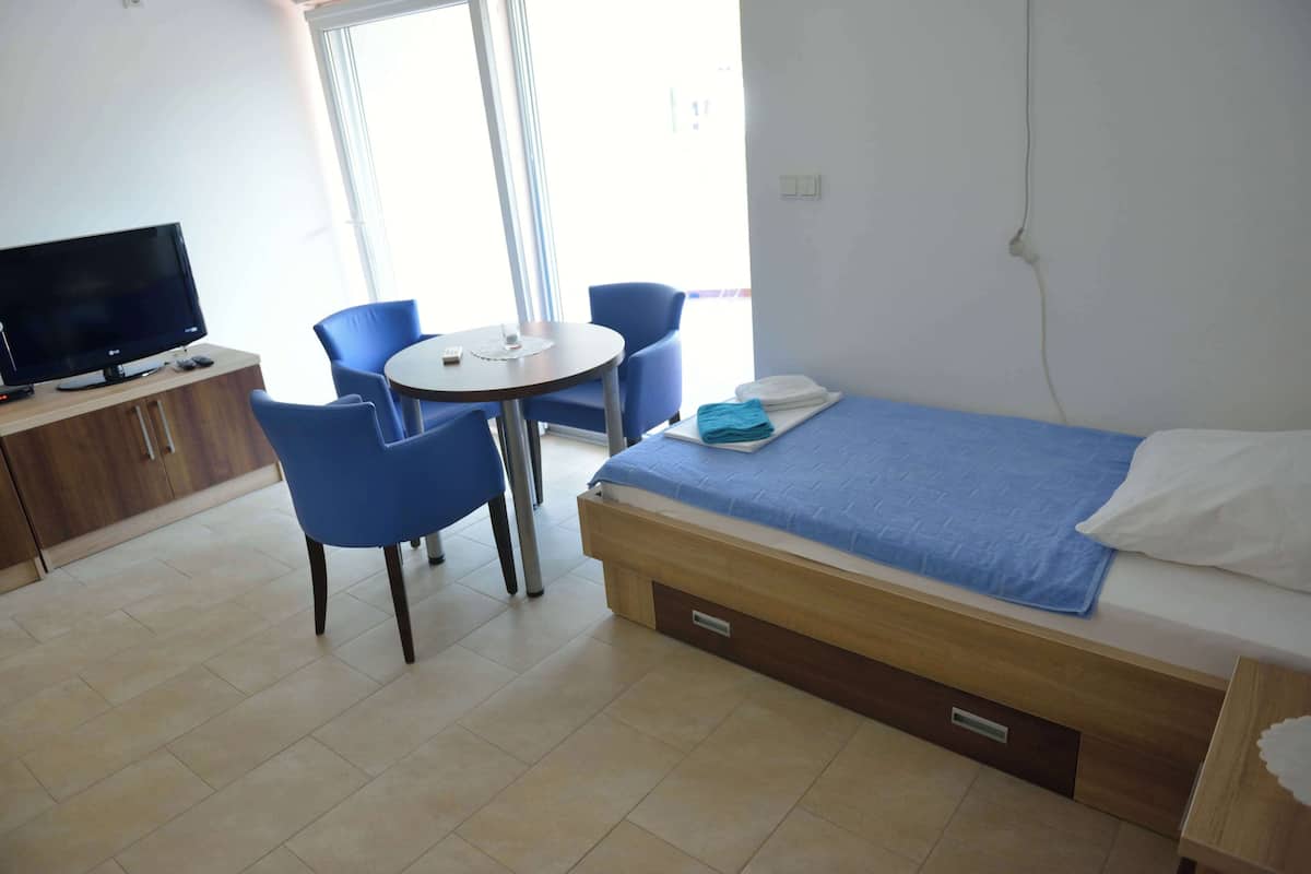 A hotel room with a bed, a desk, a chair, and a television.