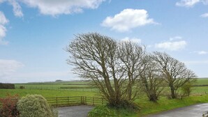 A rural landscape with a gravel path, a wooden fence, and a bench. - 3 bedroom accommodation in Hartland (Hartland)