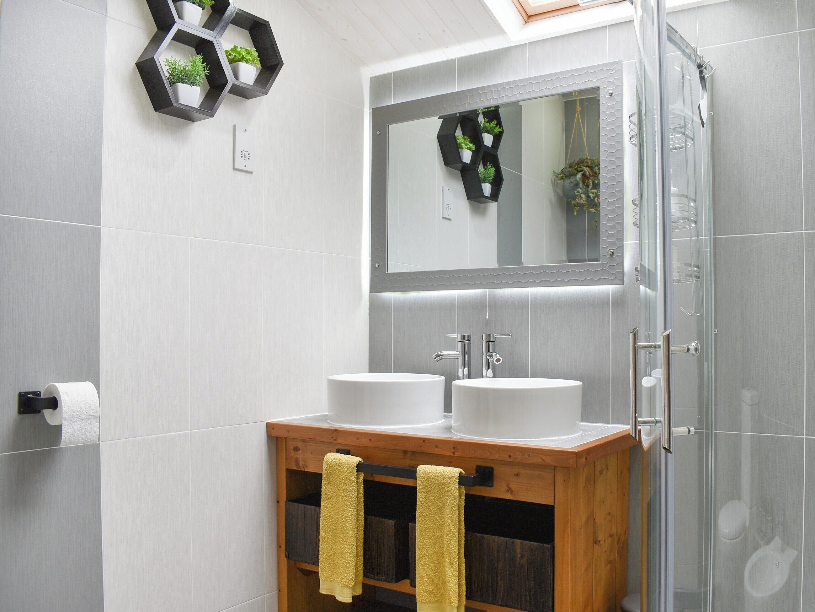 Ein modernes Badezimmer mit zwei Waschbecken, einem Spiegel und einer Dusche.