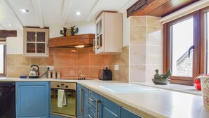 A kitchen with blue cabinets, a stove, and a window with a view. - 3 bedroom accommodation in Hartland (Hartland)