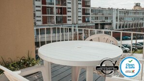 A balcony with a white table and chairs, overlooking a building with multiple windows and balconies. - Bernardo's Place (Ponta Delgada)
