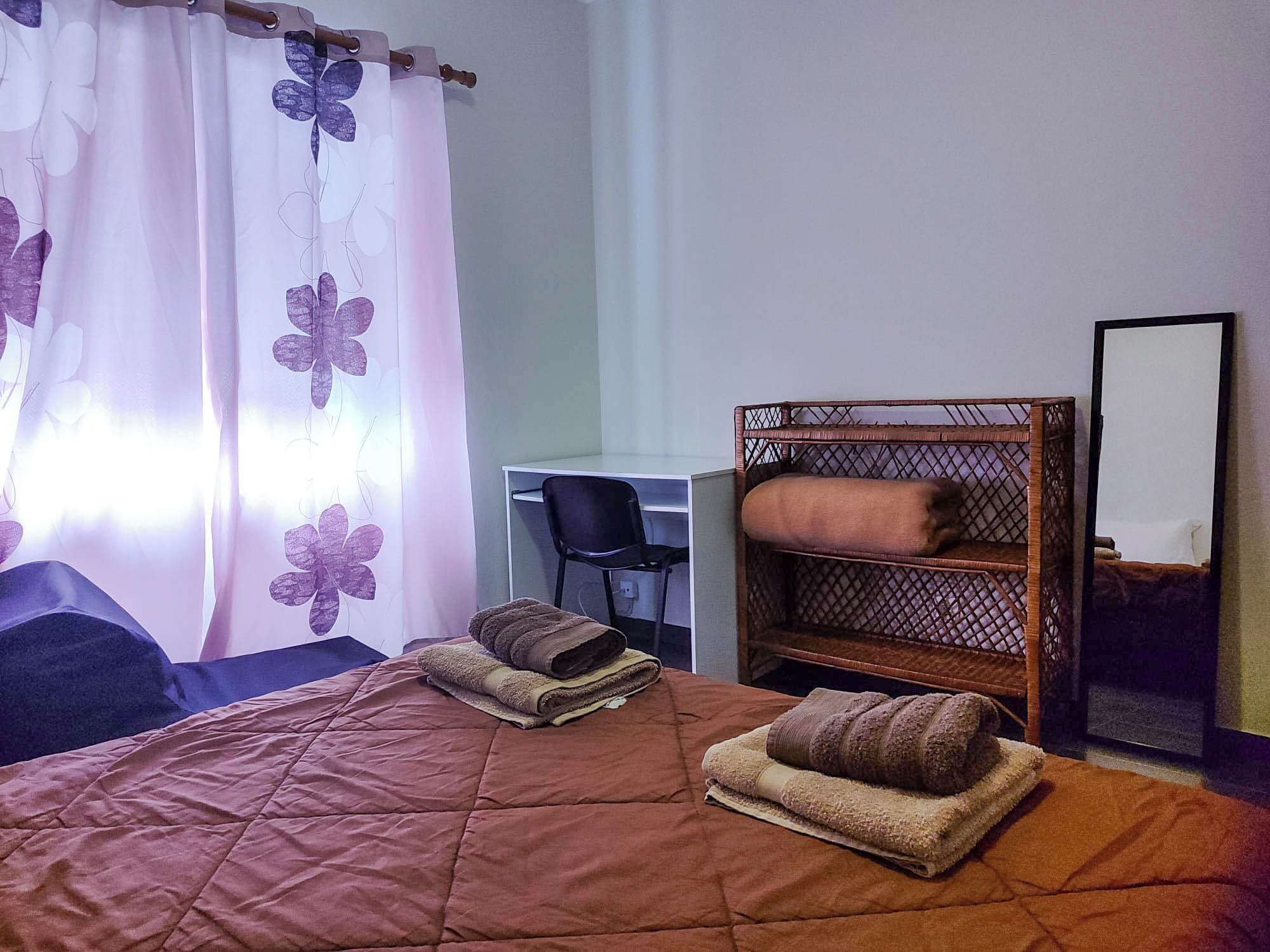 Hotellihuone, jossa on sänky, työpöytä, tuoli ja peili.