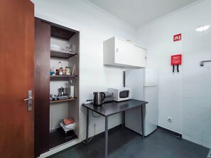 A compact kitchenette with a microwave, a small refrigerator, and a cabinet above the counter. - Bernardo's Place (Ponta Delgada)