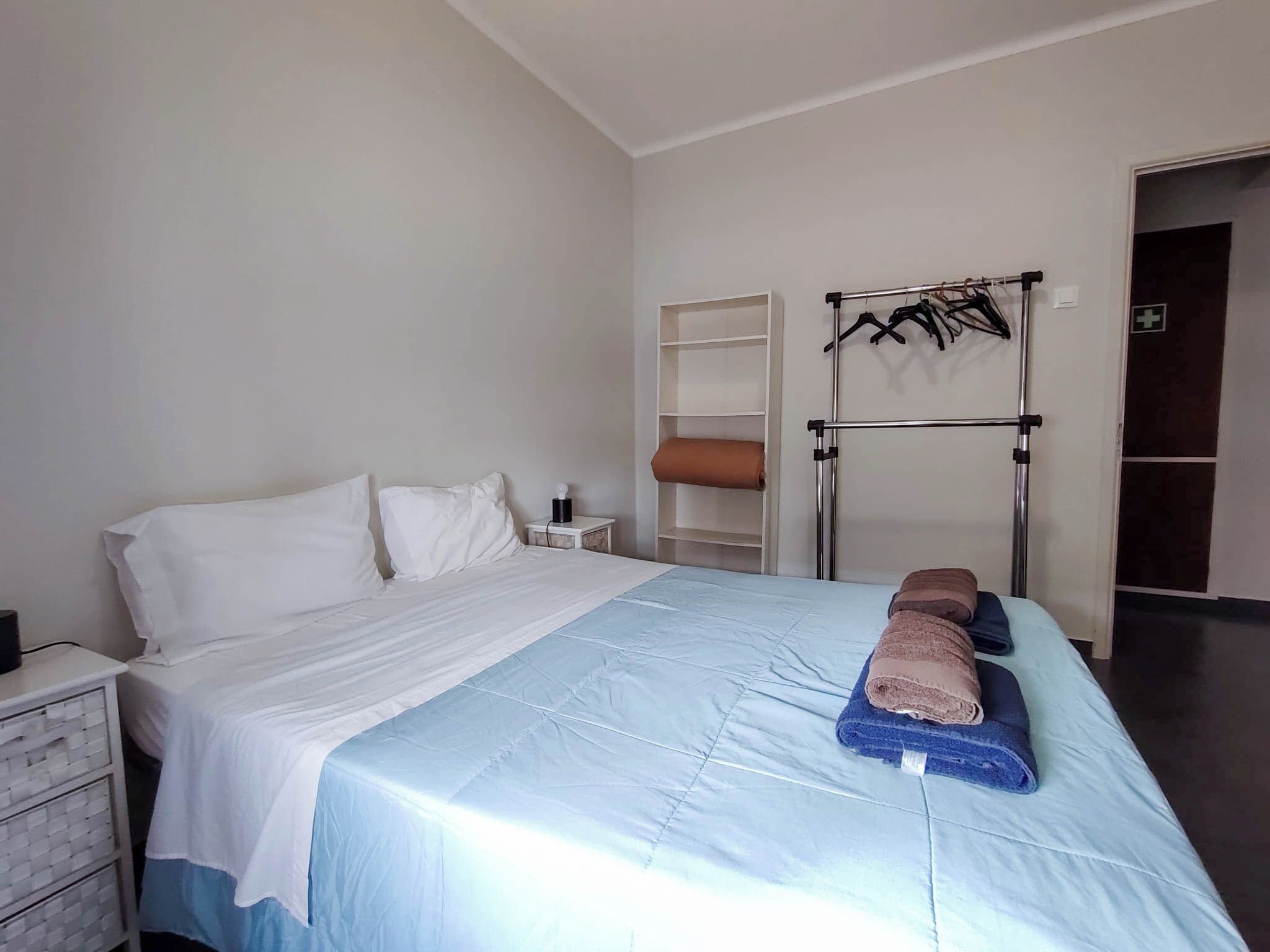 A hotel room with a bed, a nightstand, a wardrobe, and a towel rack.