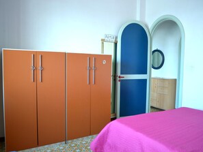 Una habitación con cama, armario, puerta y espejo.