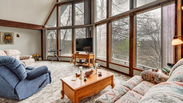 A spacious living room with a large window, a television, and a cozy seating area. - Riverfront Baxter Springs Home w/ Deck & Grill! (Baxter Springs)