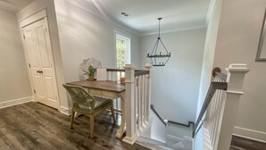 Un coin repas avec une table en bois et une chaise verte, une porte blanche et un escalier avec une rampe blanche.
