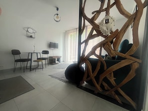A living room with a sofa, chairs, a coffee table, a TV, and a decorative tree structure.