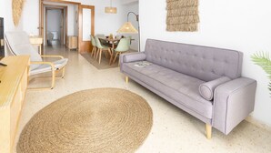 A living room with a sofa, a dining table with chairs, a TV, and a lamp. - A (VA068) TH Port Saplaya con vistas al Mar. (Alboraya / Alboraia)