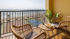 A balcony with wicker chairs, a small table with a bottle and glasses, and a view of the beach and tennis court. - A (VA068) TH Port Saplaya con vistas al Mar. (Alboraya / Alboraia)