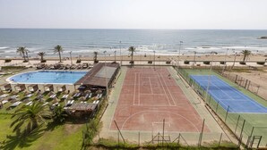 A beachside resort with a swimming pool, tennis courts, and beach umbrellas. - A (VA068) TH Port Saplaya con vistas al Mar. (Alboraya / Alboraia)