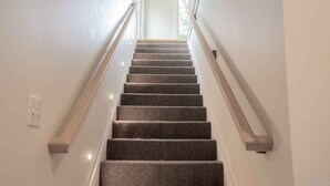 Una escalera con barandillas y alfombra, que lleva a una puerta en la parte superior.