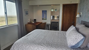 Ein Hotelzimmer mit Bett, Schreibtisch, Kühlschrank und Mikrowelle.