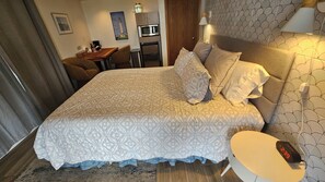 Una habitación de hotel con cama, mesita de noche, lámpara y escritorio con silla.