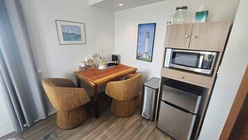 Une petite cuisine équipée d’un four à micro-ondes, d’un réfrigérateur et d’une petite table à manger avec des chaises.