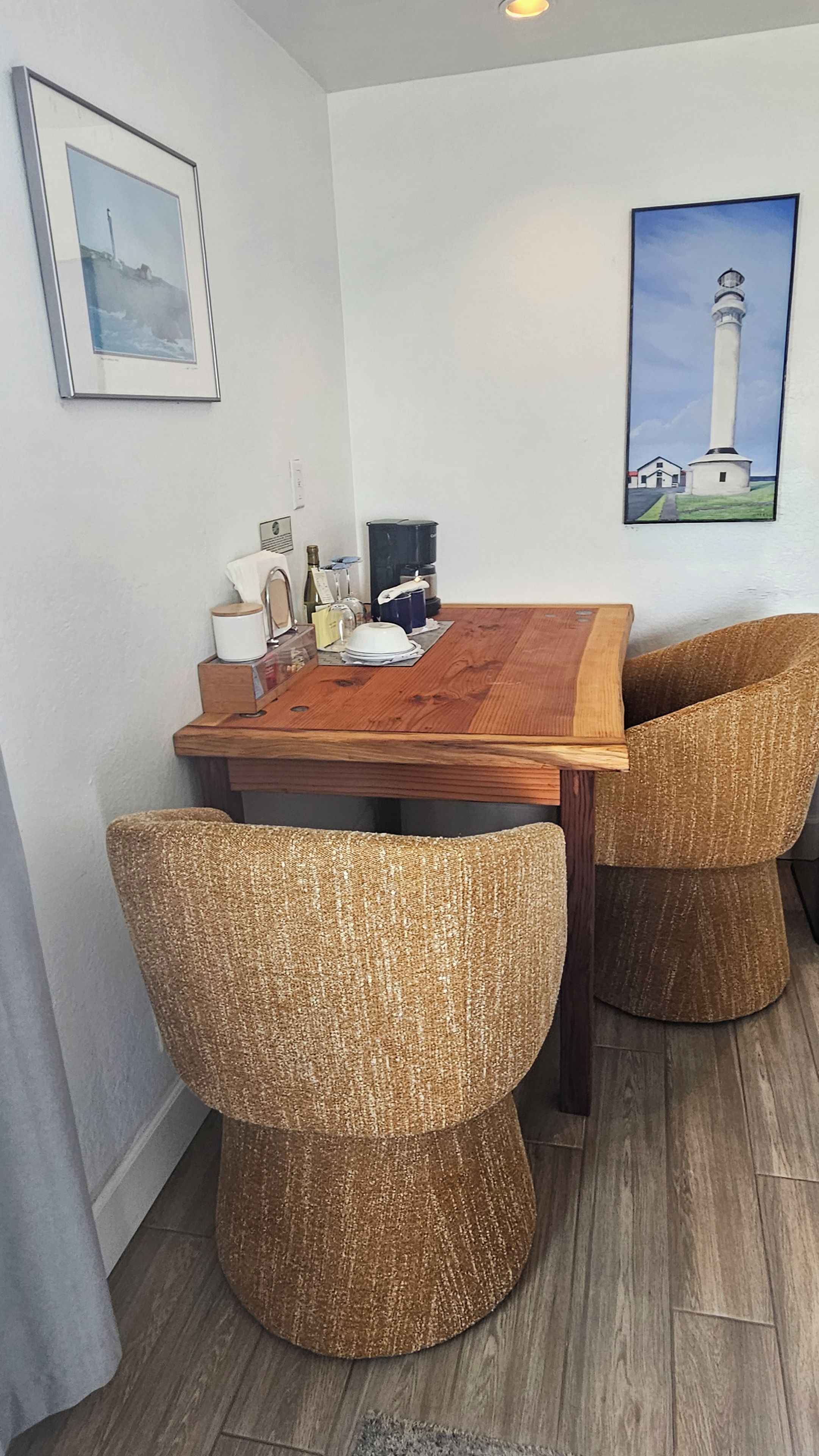 A dining area with a wooden table, wicker chairs, and artwork on the walls.