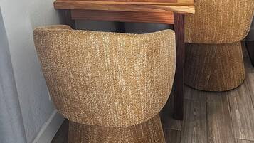 A dining area with a wooden table, wicker chairs, and artwork on the walls.