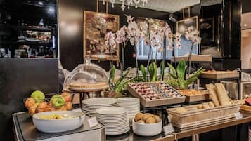 A buffet setup with various food items, including fruits, pastries, and condiments.