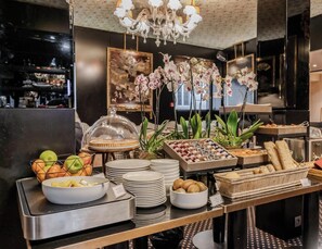 A buffet setup with various food items, including fruits, pastries, and condiments.