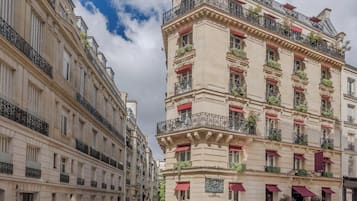 A multi-story building with balconies, red awnings, and a plaque on the facade.