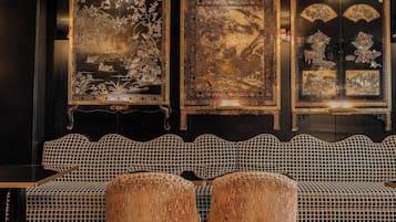 A room with a black and white checkered sofa, three traditional paintings on the wall, and a small table.