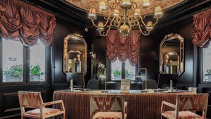 A hotel lobby with a reception desk, two chairs, a chandelier, and large mirrors. - Hotiday Room Collection - Paris Arc de Triomphe (Paris)