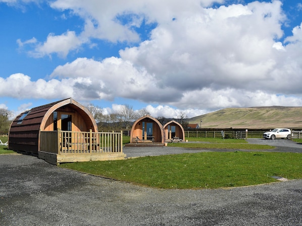A row of wooden cabins with a wooden deck and a car parked nearby.