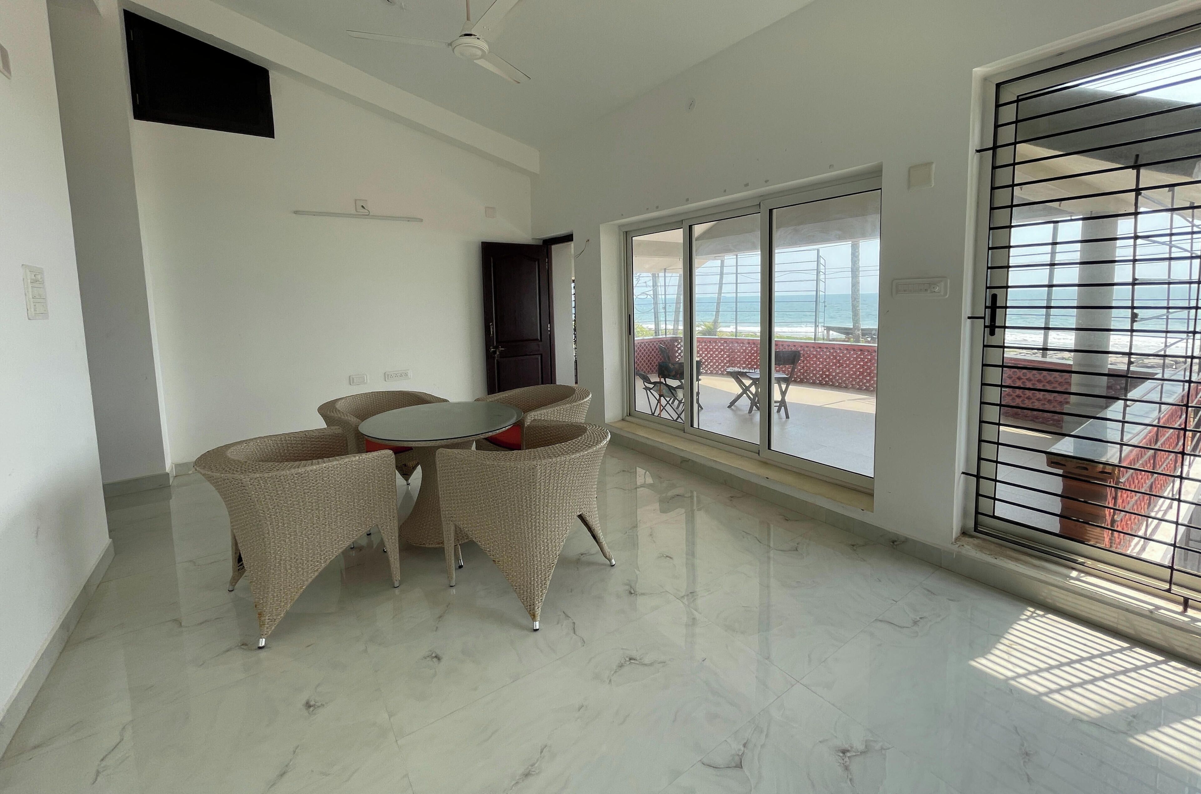 A room with a glass door leading to a balcony with a view of the sea.