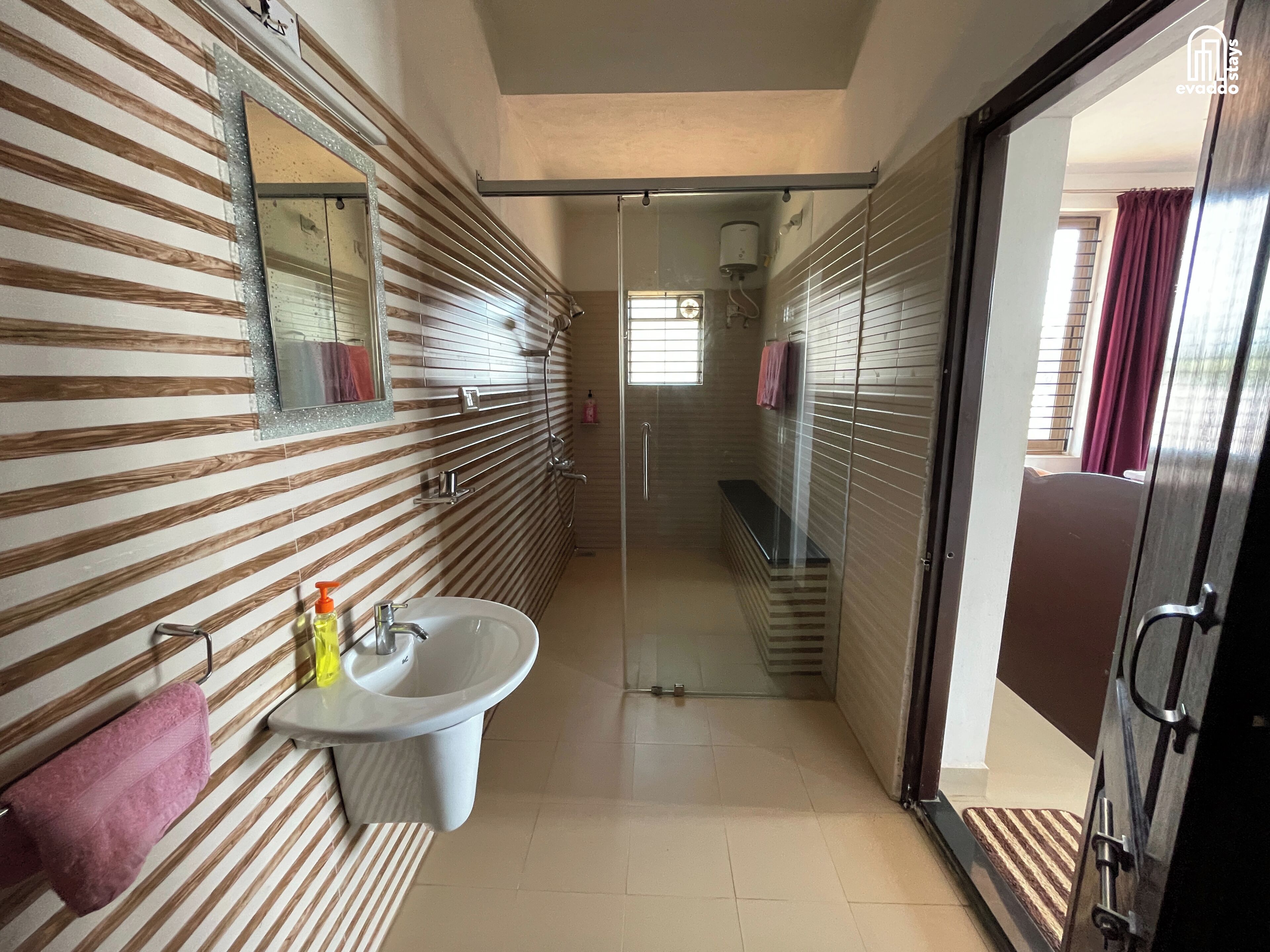 Un baño moderno con un diseño de pared a rayas, un lavamanos y una cabina de ducha con mampara de vidrio.