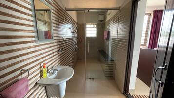 Un baño moderno con un diseño de pared a rayas, un lavamanos y una cabina de ducha con mampara de vidrio.