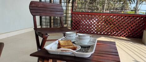A wooden table with a tray containing a cup, a teapot, and a plate with toast and a sandwich.